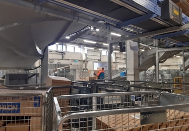 Bild från en paketterminal. Man ser paketburar och en terminalarbetare.