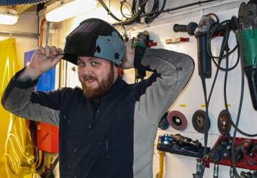 En man som lyfter av sig sin svetsmask.