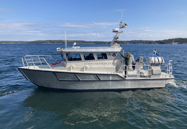 En mindre båt från Försvarsmakten åker på ett blått hav.