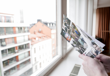 Någon läser en Seko-broschyr och blickar ut över Hagagatan genom ett fönster på sjätte våningen.