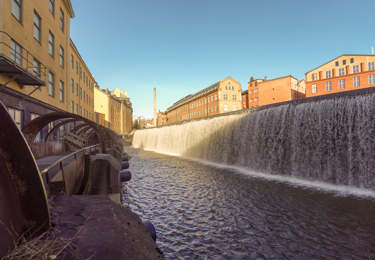 Stadsbild från Norrköping, vattendrag som rinner mellan äldre stenhus.