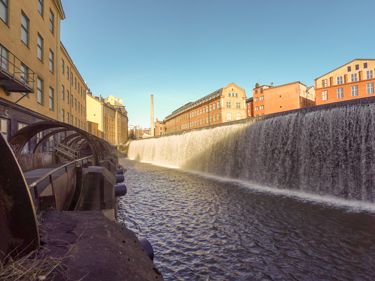 Stadsbild från Norrköping, vattendrag som rinner mellan äldre stenhus.