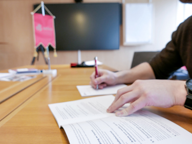 Någon läser ur ett kollektivavtal och gör anteckningar.. Den som läser sitter vid ett mötesbord på en utbildning.