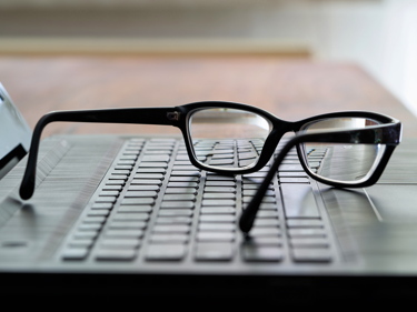 Glasögon liggande på ett tangentbord.