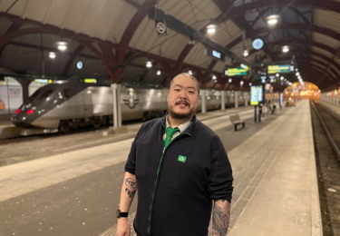 En tågvärd på SJ i arbetskläder står på en tågperrong.