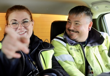 En kvinnlig och en manlig Seko-medlem på Swedavia sitter bredvid varandra, de skrattar och kvinnan pekar mot kameran.