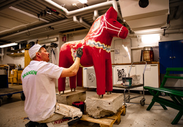 En Seko-medlem på Skansen målar en stor dalahäst.