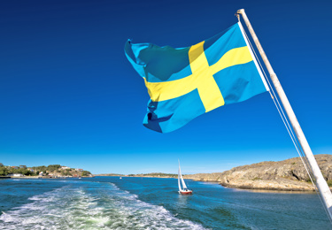 Skärgårdsbild med flagga på båt.