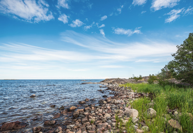Stenstrand vid havet en sommardag.