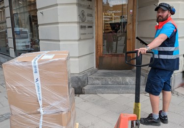 En chaufför i PostNorduniform med handtruck
